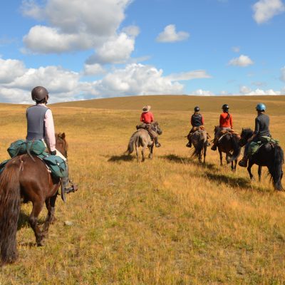 horseback riding in Mongolia, open grasslands and blue sky